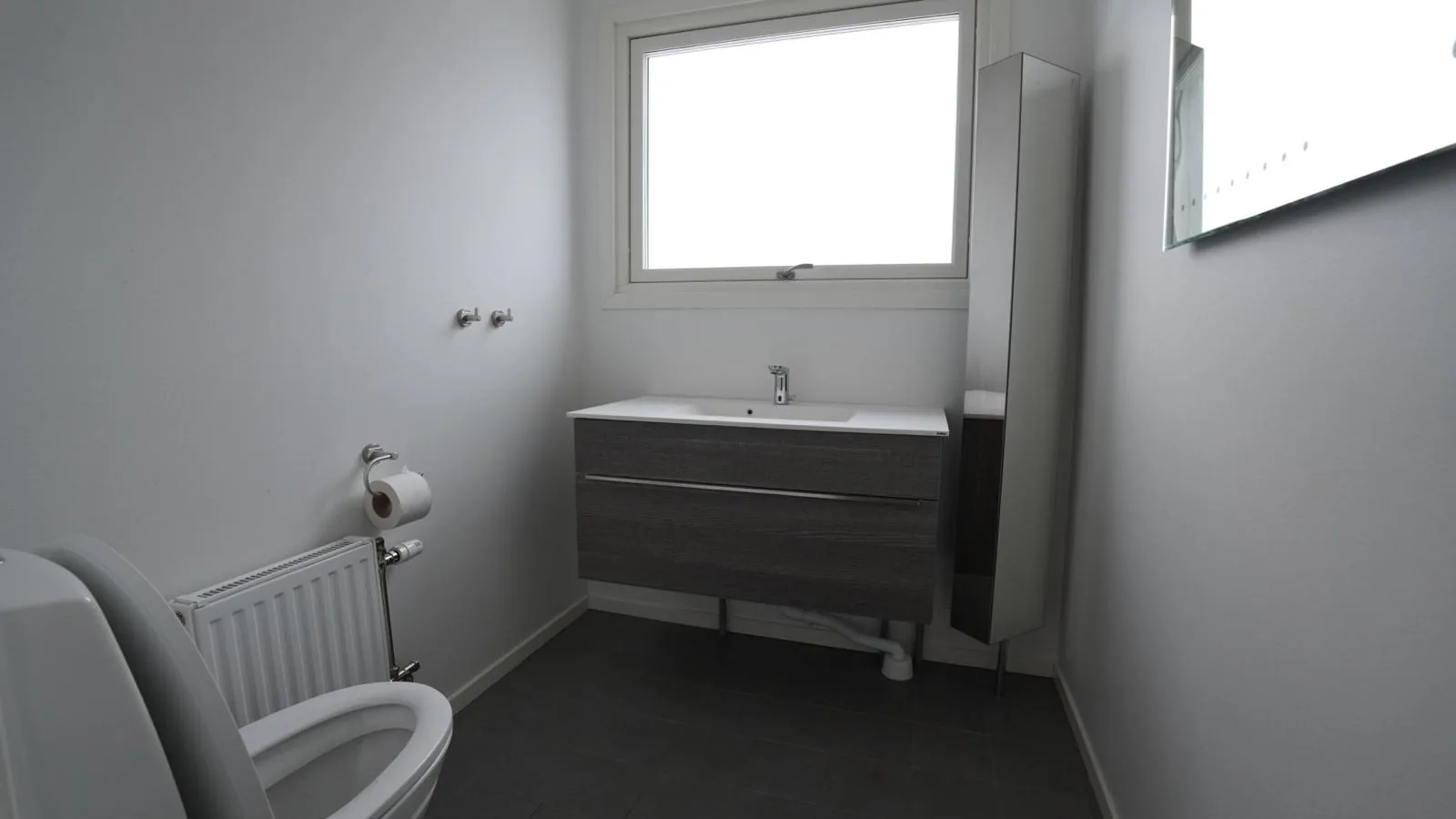 Badrum med kommod, spegelskåp och fönster