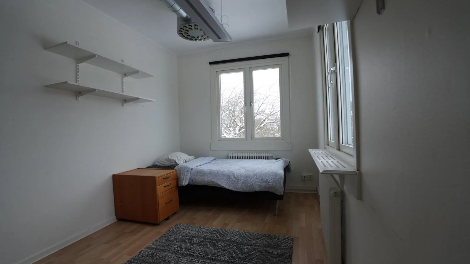 Enkelrum med säng, väggyllor och byrå