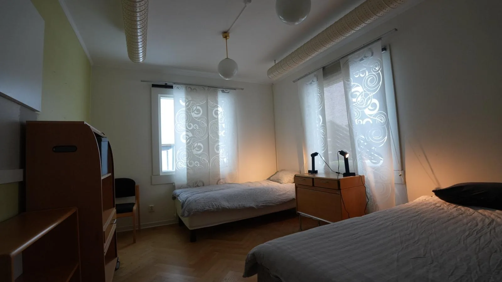 Sovrum med två sängar och läslampor i kvällsljus