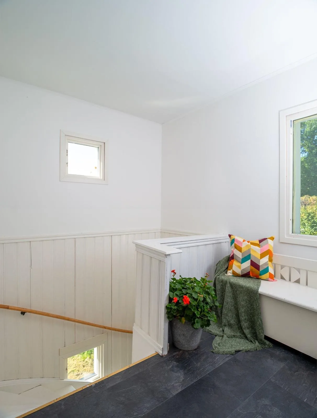 Trapphus med vitmålad panel och inbyggd sittbank vid fönstret